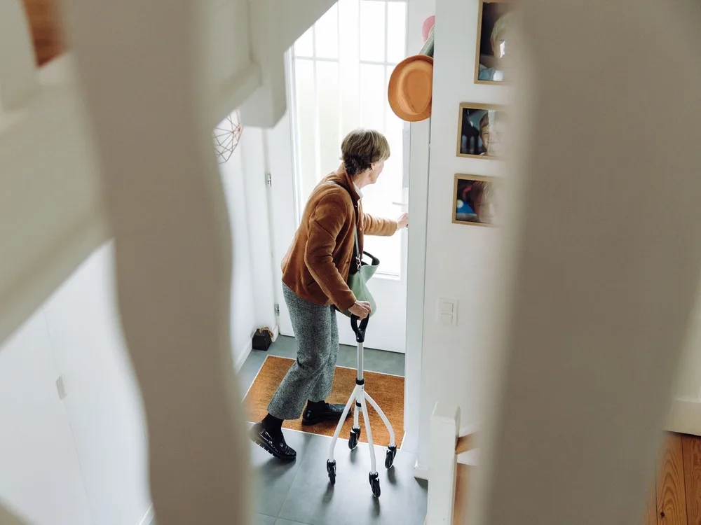 An older woman using a rollator while moving through the entrance of her home